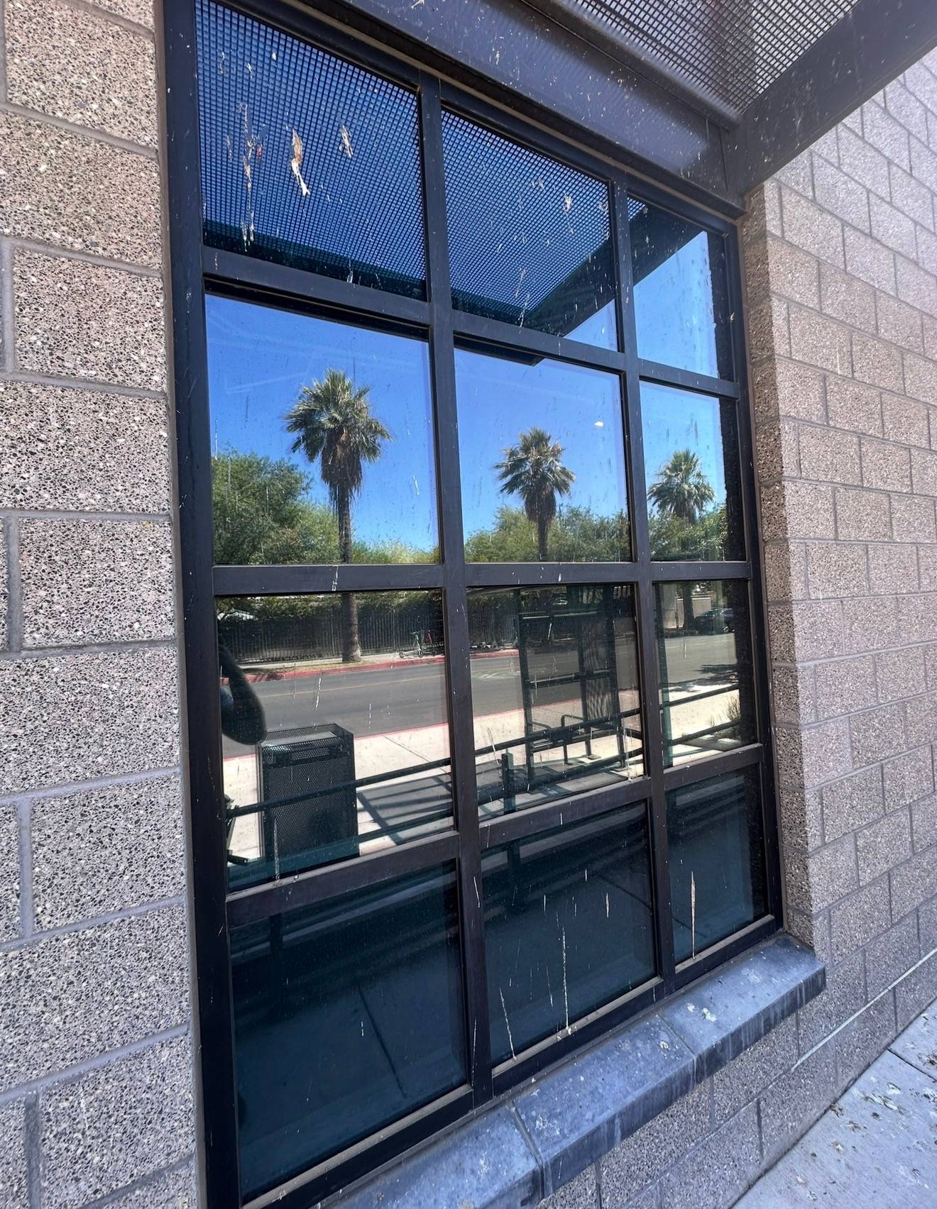 A commercial storefront window before cleaning, spotted with dried spatter