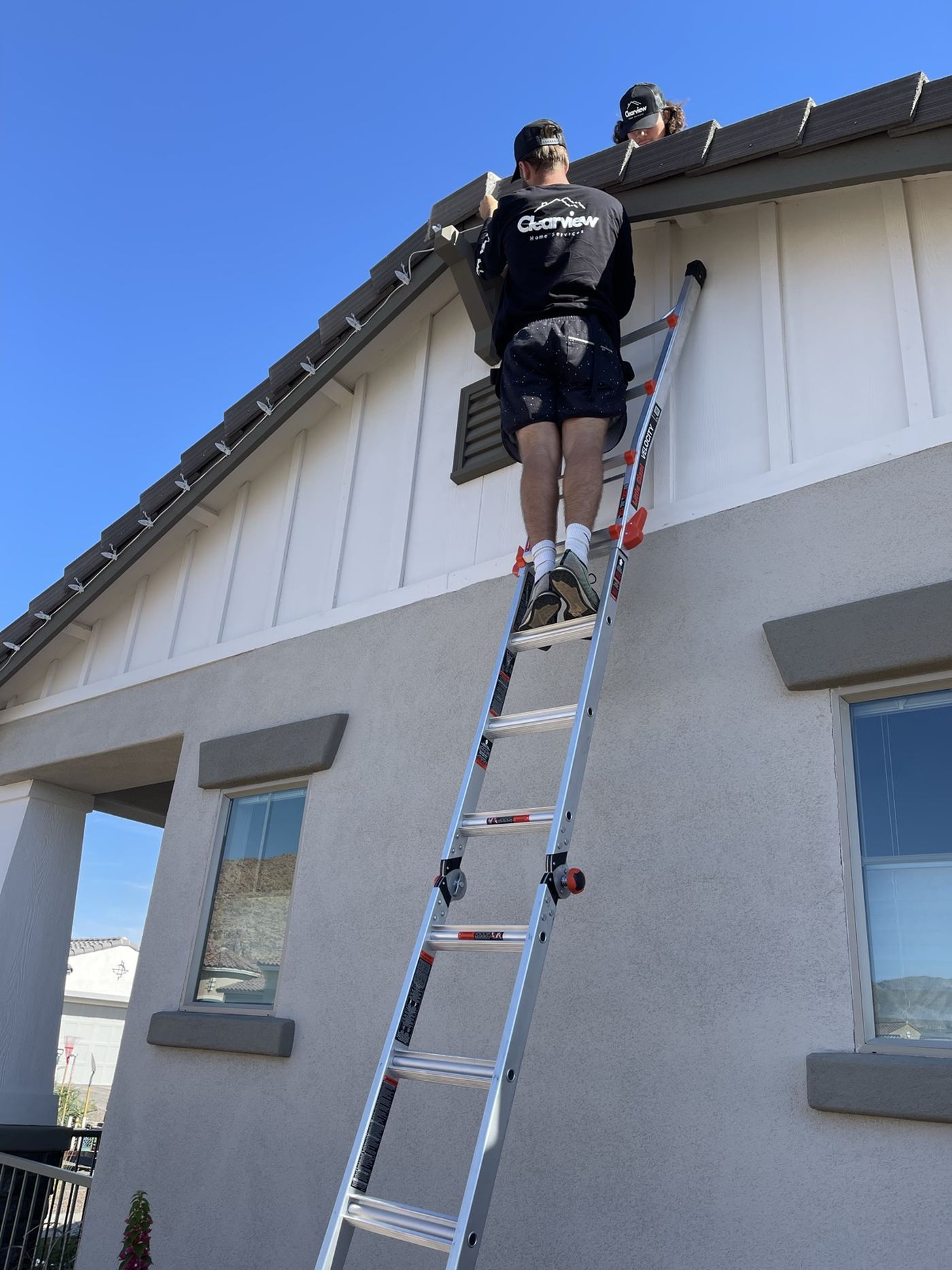 Two Vero technicians working the upper windows of a two-story home